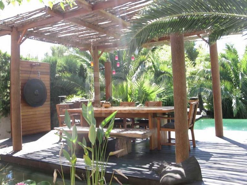 pergola with dining area in an exotic garden next to a modern house located in Marseille
